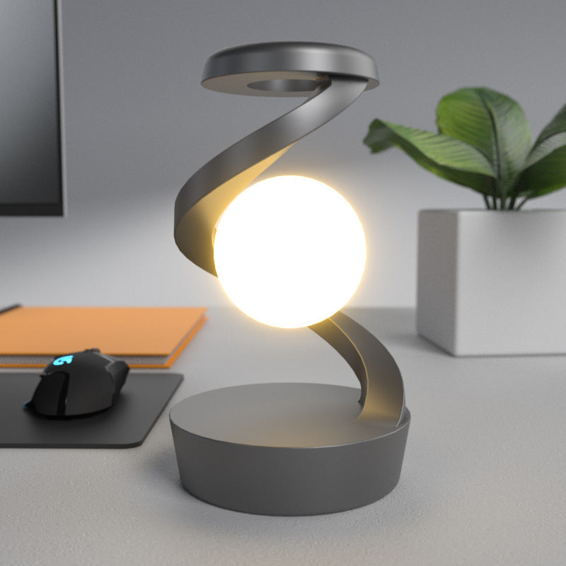 Draaiende maanlamp in metalen spiraal op bureau