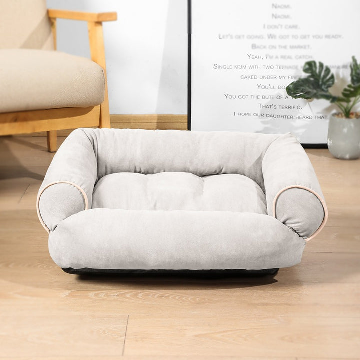 Hond ligt op een grijze pluche hondensofa