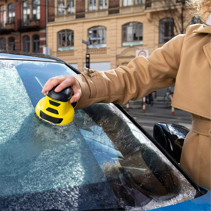 Gele elektrische ijskrabber op een bevroren autoruit